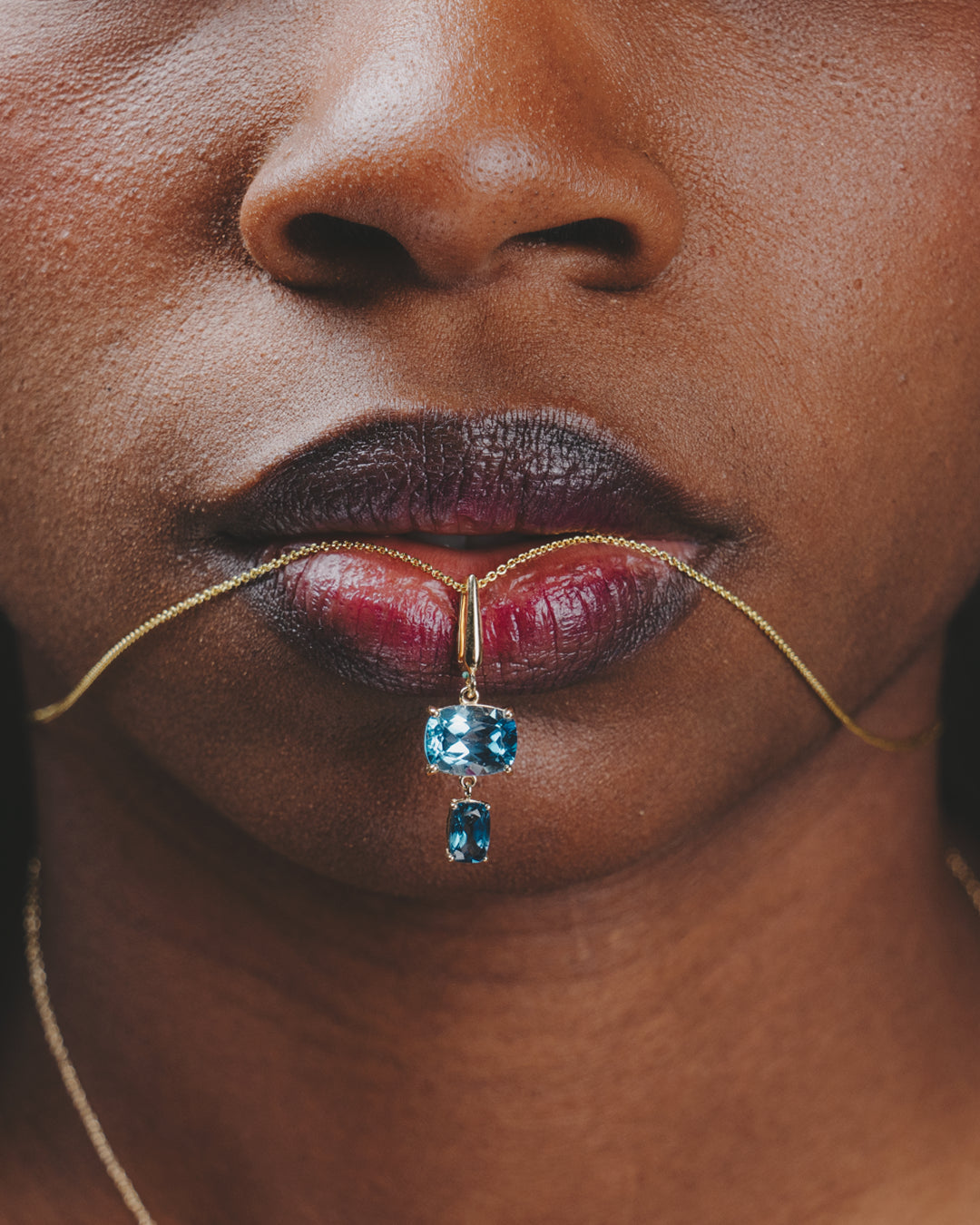 Modelo con el collar de topacio azul london en sus labios