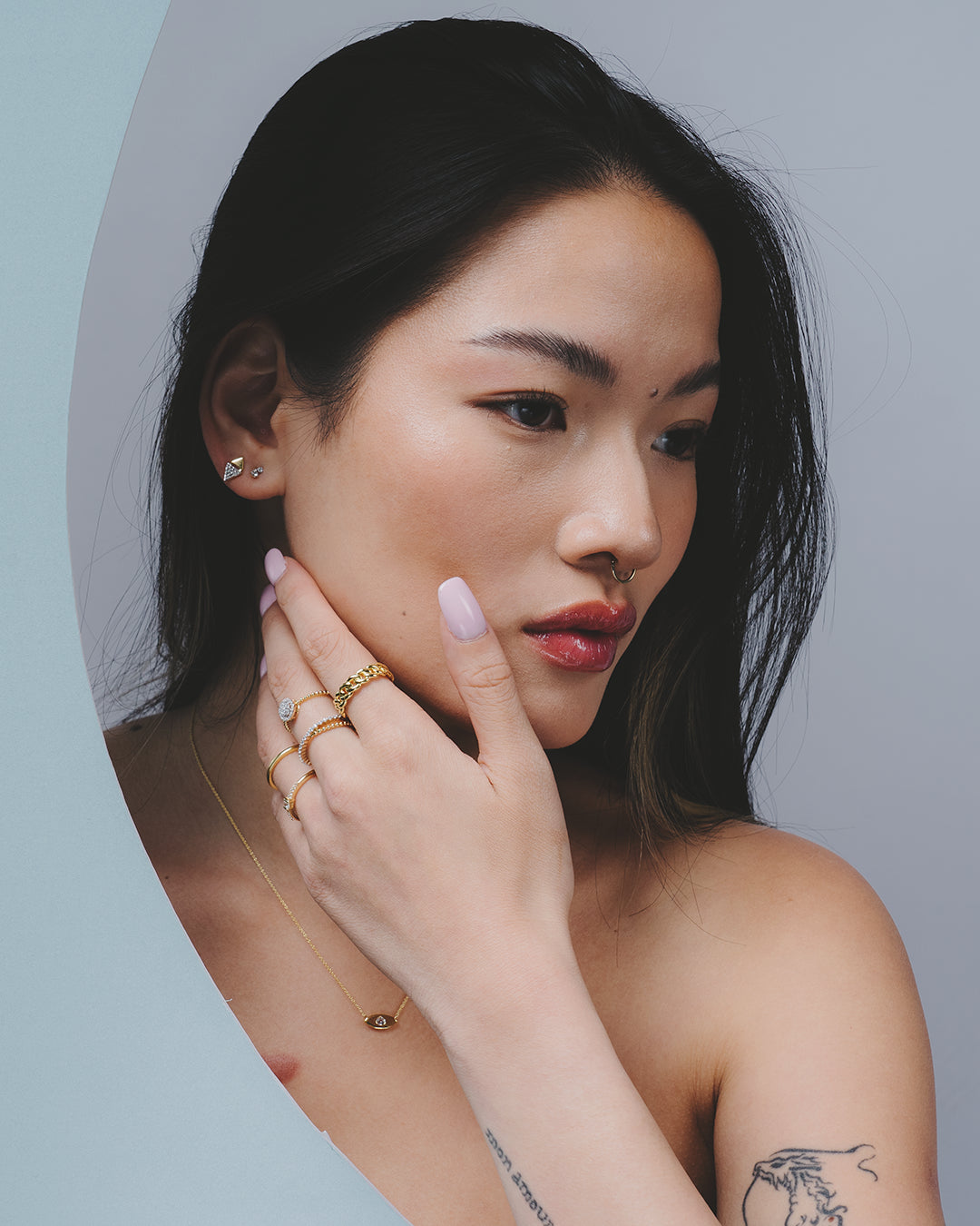 Modelo con la mano en la cara presentando varios anillos de la colección