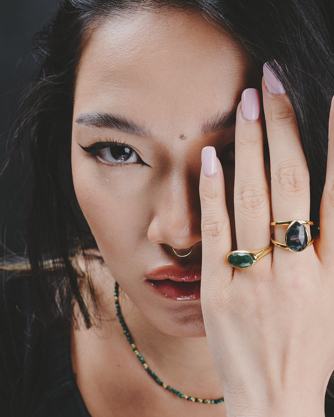 Modelo con la mano en la cara enseñando dos anillos de la colección