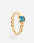 Anillo de plata chapado en oro entrelazado con un topacio azul en el centro