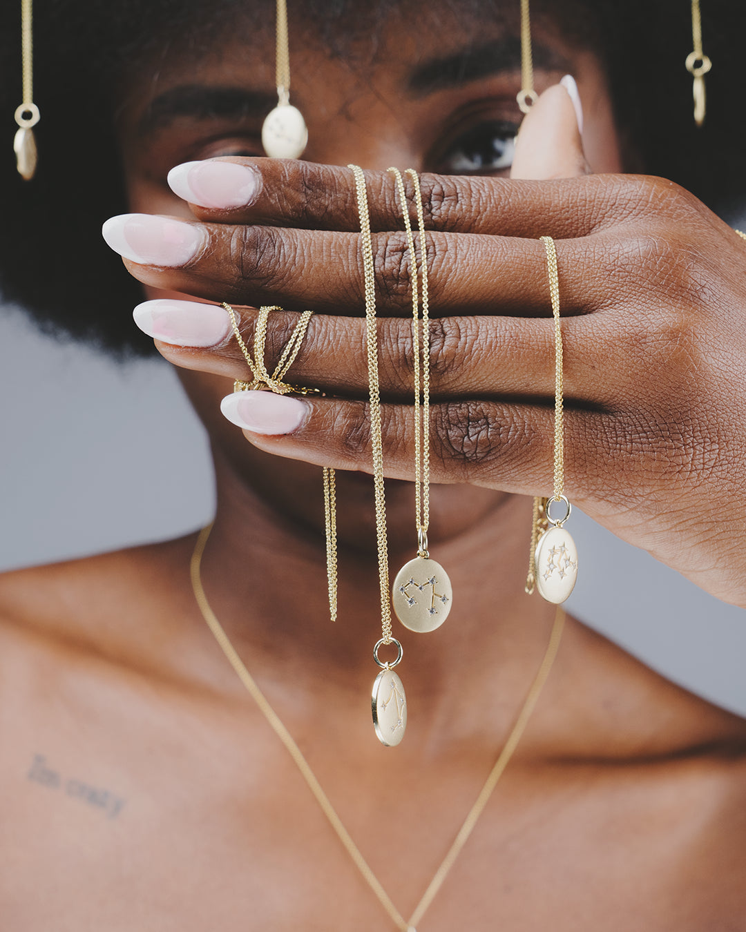 Modelo con su mano en primer plano enseñando varios collares de la colección del Zodiaco