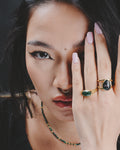 Modelo con la mano en la cara enseñando dos anillos de la colección